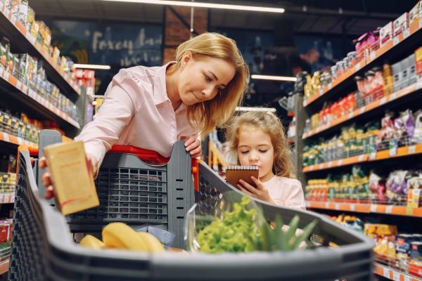 Family at the supermarket. Woman in a pink shirt. People choose products. Mother with daughter.